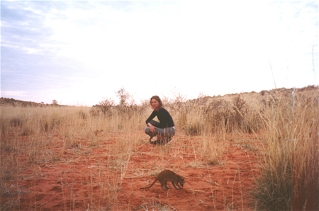 Woman with meerkat foraging in foreground